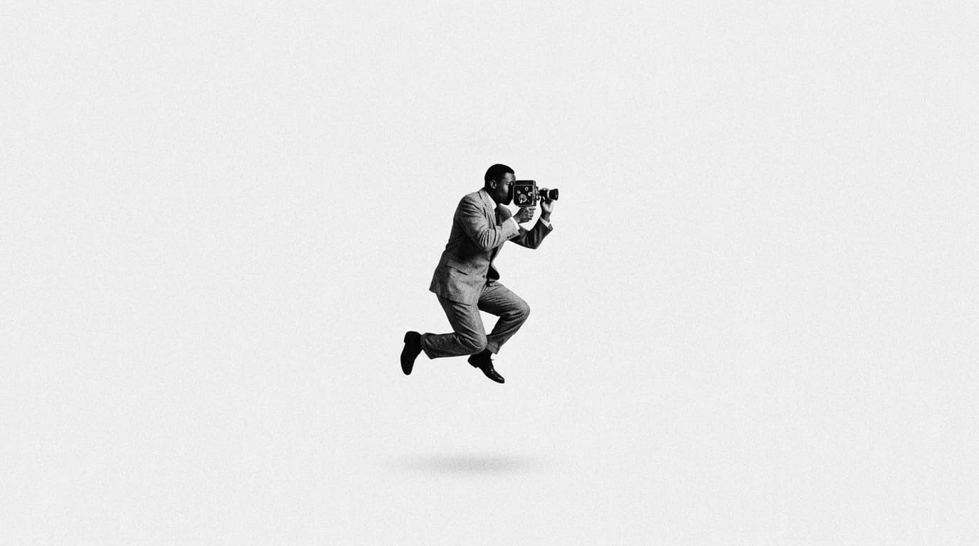 A man in a suit jumping with an old film camera to his eye